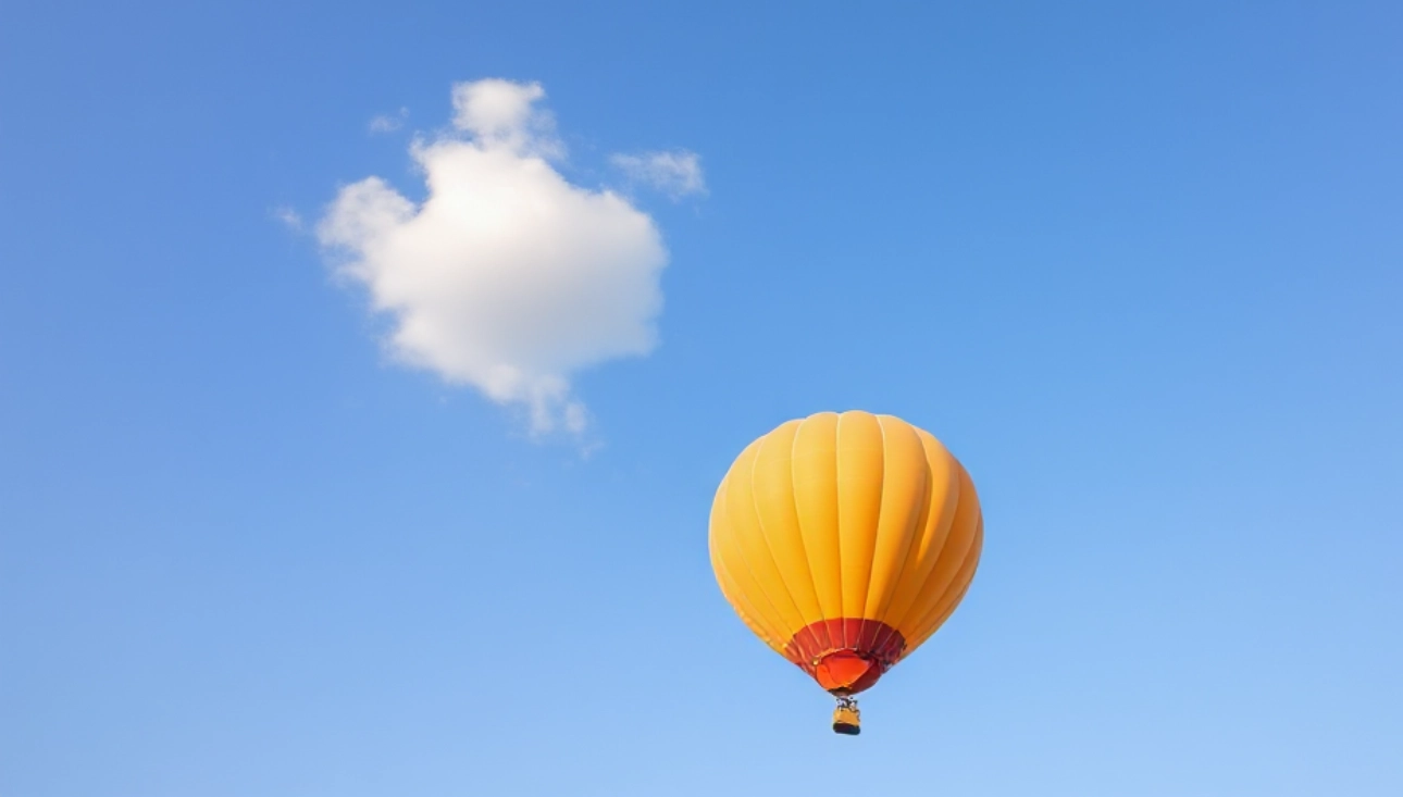 Orangener Heißluftballon vor dem Hintergrund eines klaren blauen Himels mit nur einer lustigen kleinen Wolke als Sinnbild für unseren Freiraum.