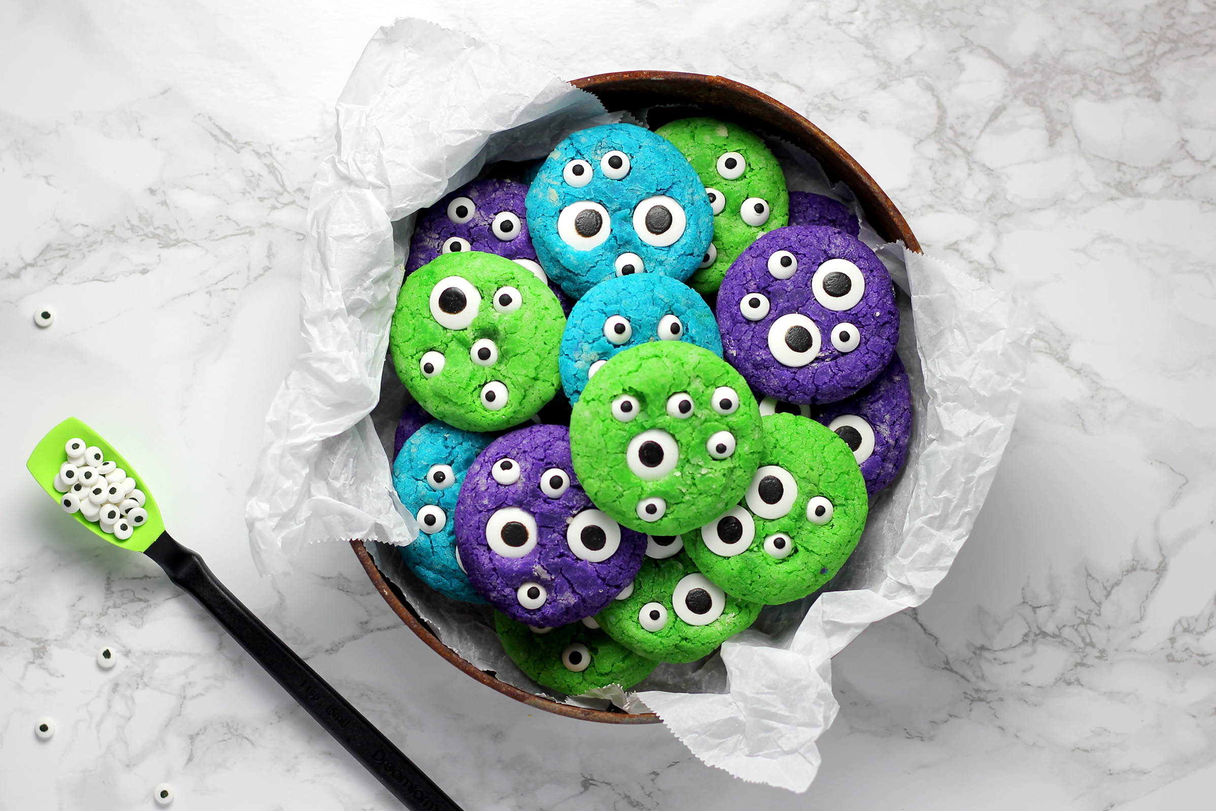 Bild einer Schale grüner, türkiser und lilaner Cookies mit haufenweise Augen aus Zucker darauf, als Sinnbild für die Cookies, die im Web genutzt werden.